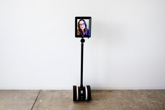 a telepresence robot from Double Robotics in the form of an iPad on a stick on a Segway-like base. The iPad shows a female’s face