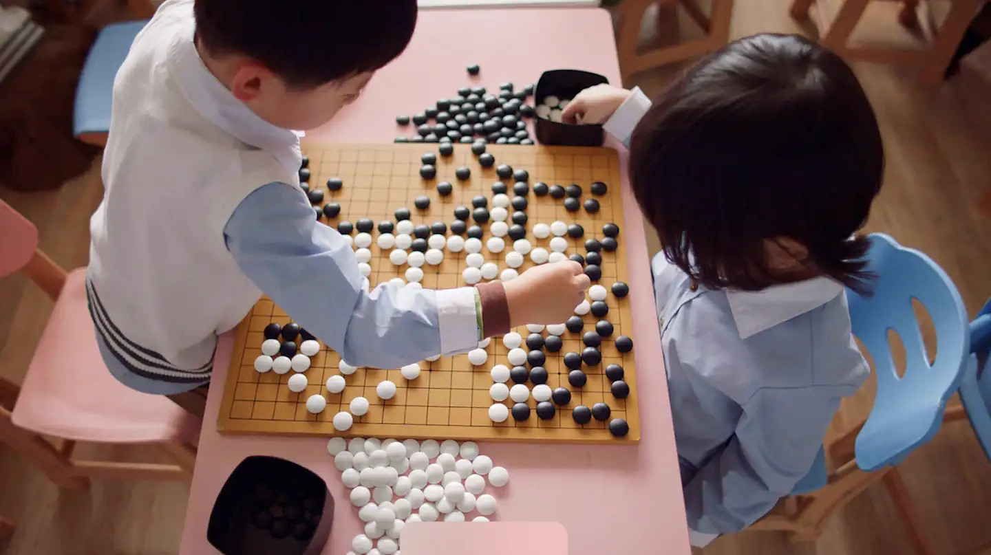 Two Chinese children playing the board game Go with black and white stones