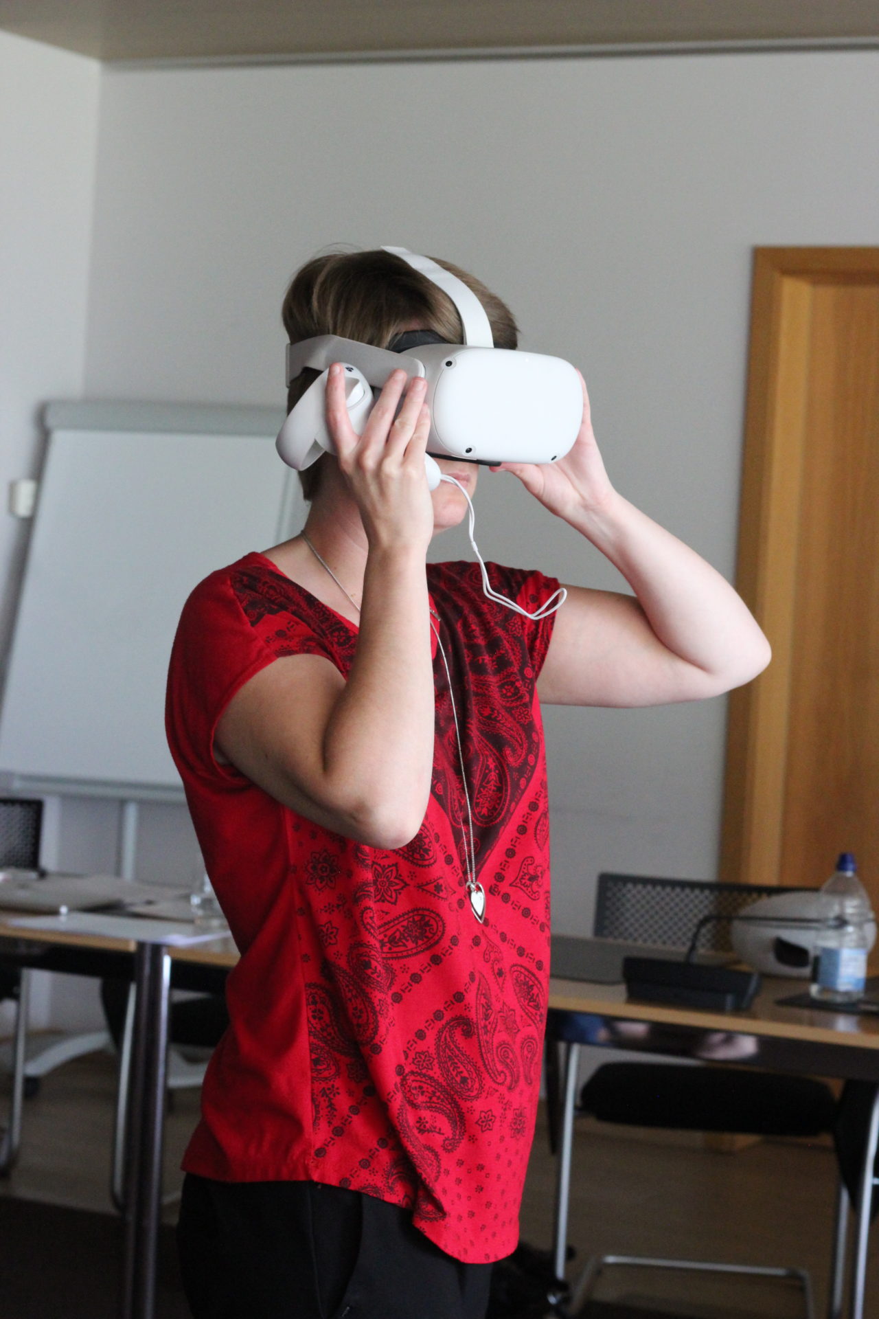 Christina Stimson is stood up wearing a virtual reality headset as she demonstrates robot telepresence.