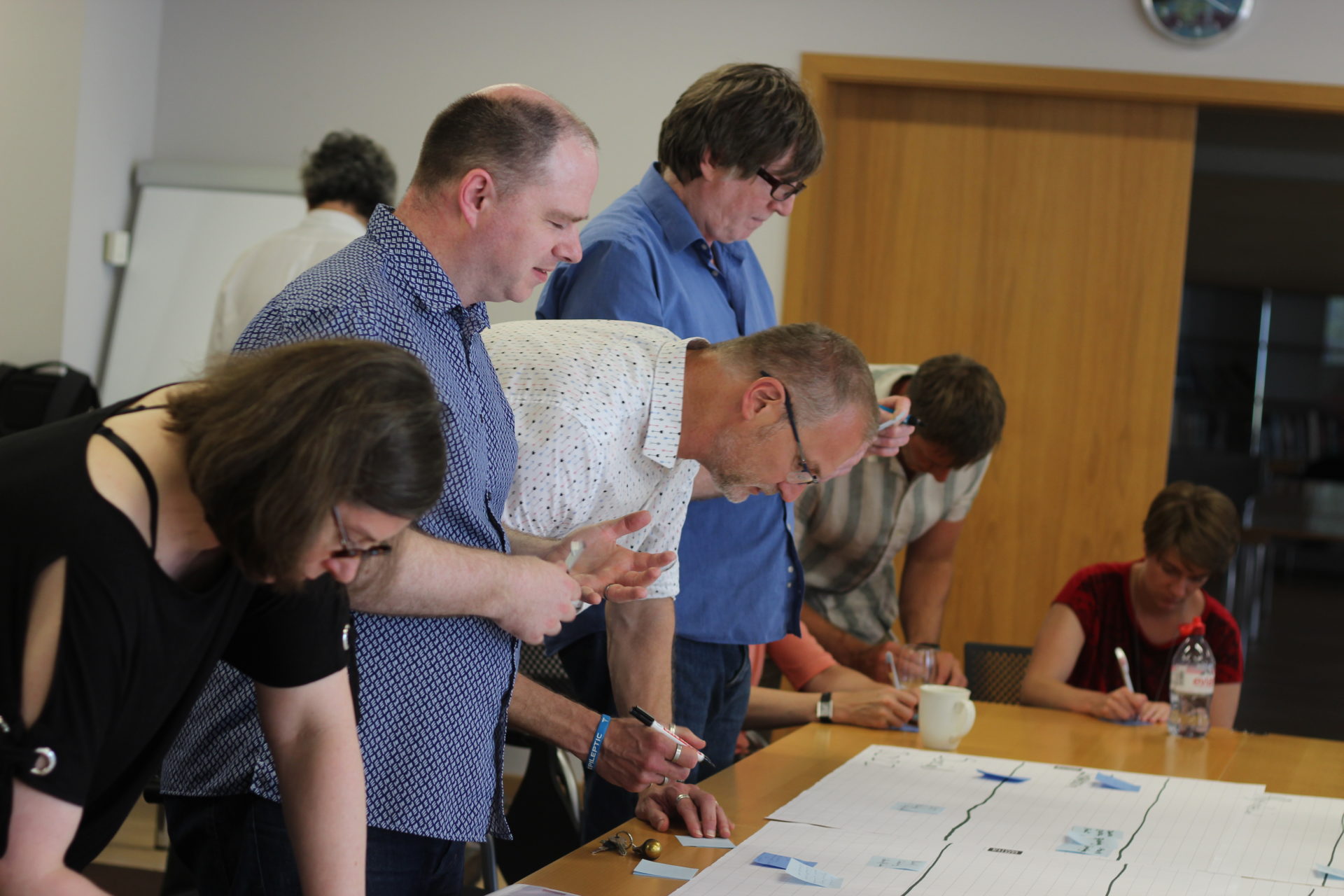 6 Workshop participants continue to elaborate on the timeline, looking at papers spread across a table