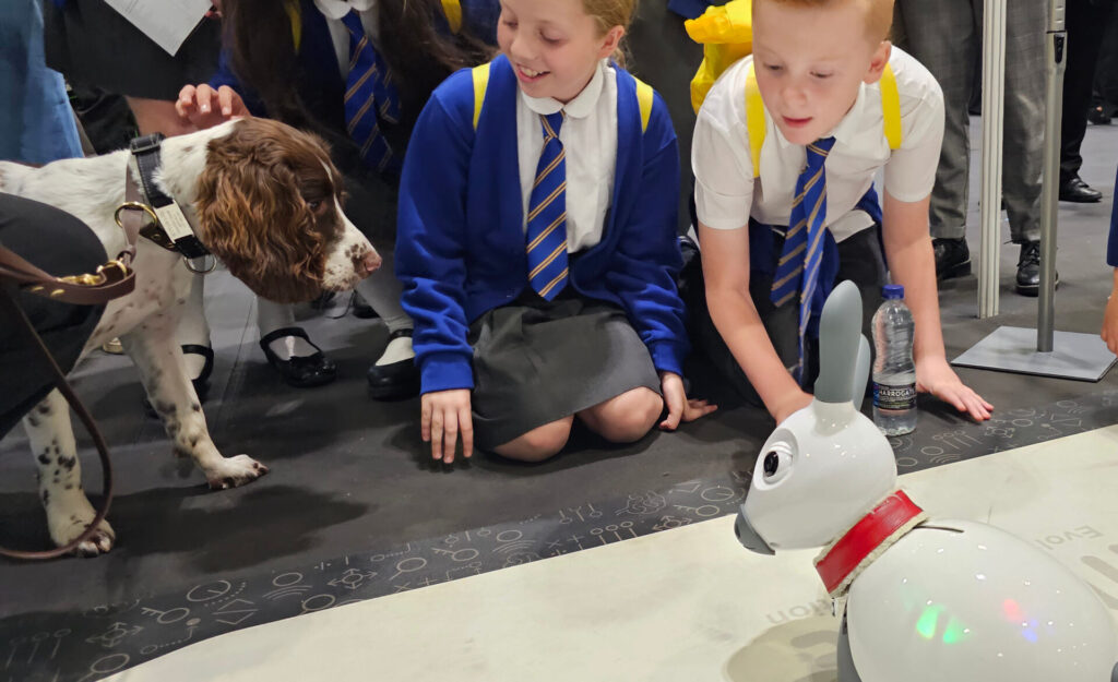 A dog and children play with a robotic dog.